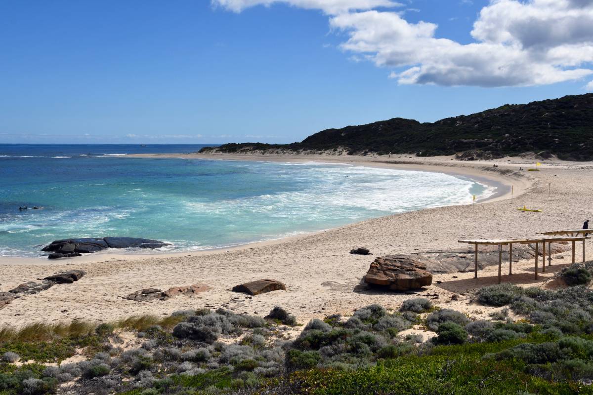 calm bay with turquoise ocean and sandy beach with sun shimmering on the water