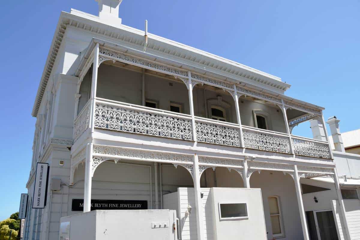 a white victorian regency style historic building with white wrought iron verandahs