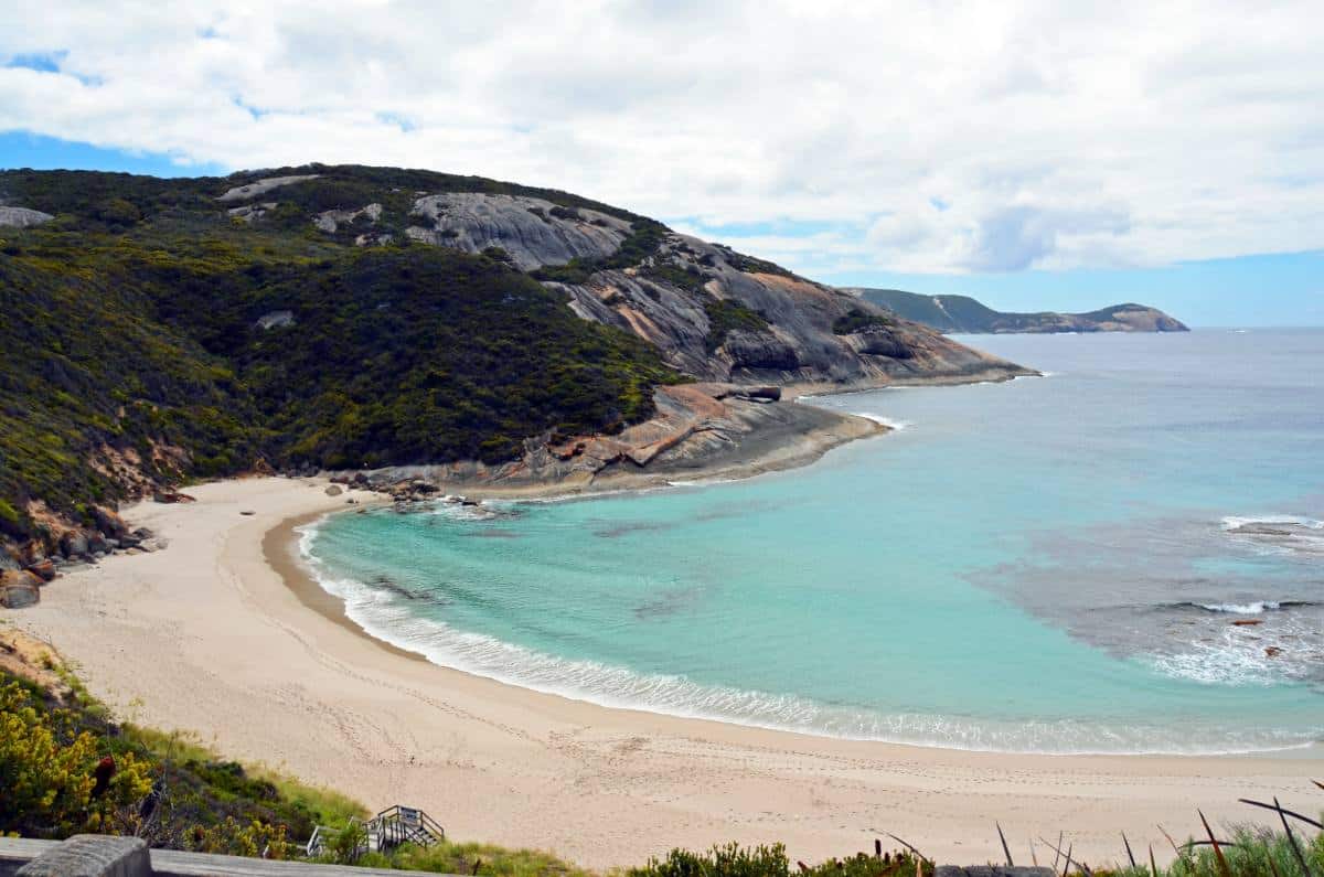 the pretty small white sand bay called Salmon Beach with calm turquoise clear water with rocks on the coastline