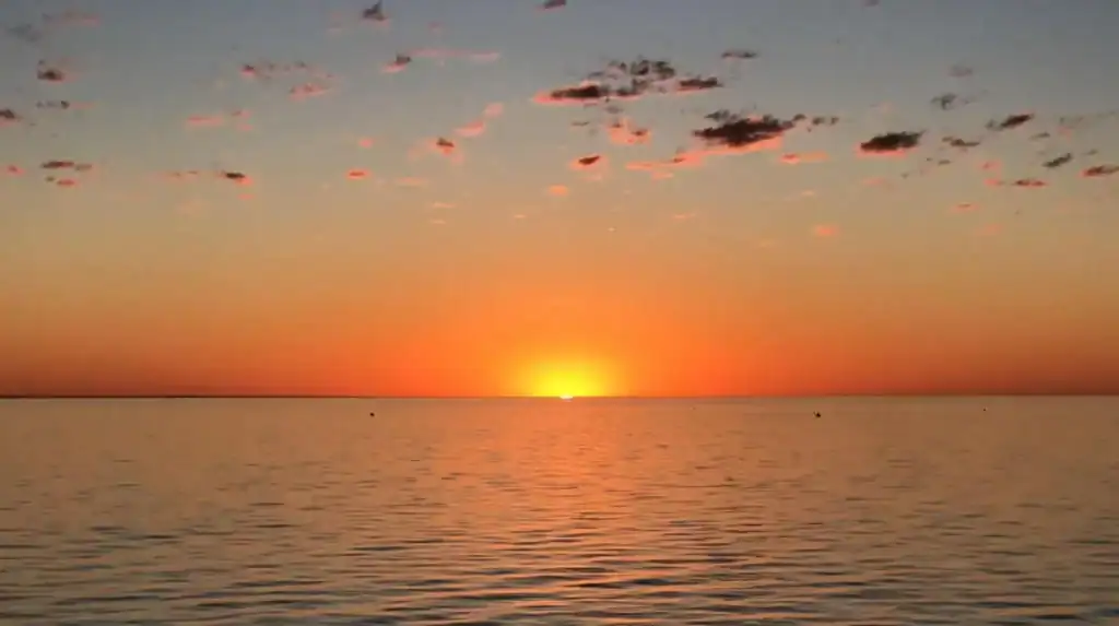 Best Things To Do in Monkey Mia Shark Bay 43 the orange sun setting behind the ocean with a warm orange glow