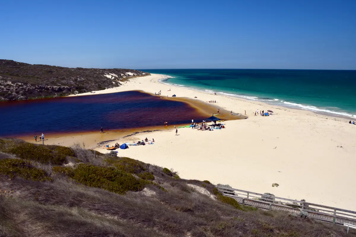 white sand creating sand bar blocking brown coloured river from entering the ocean