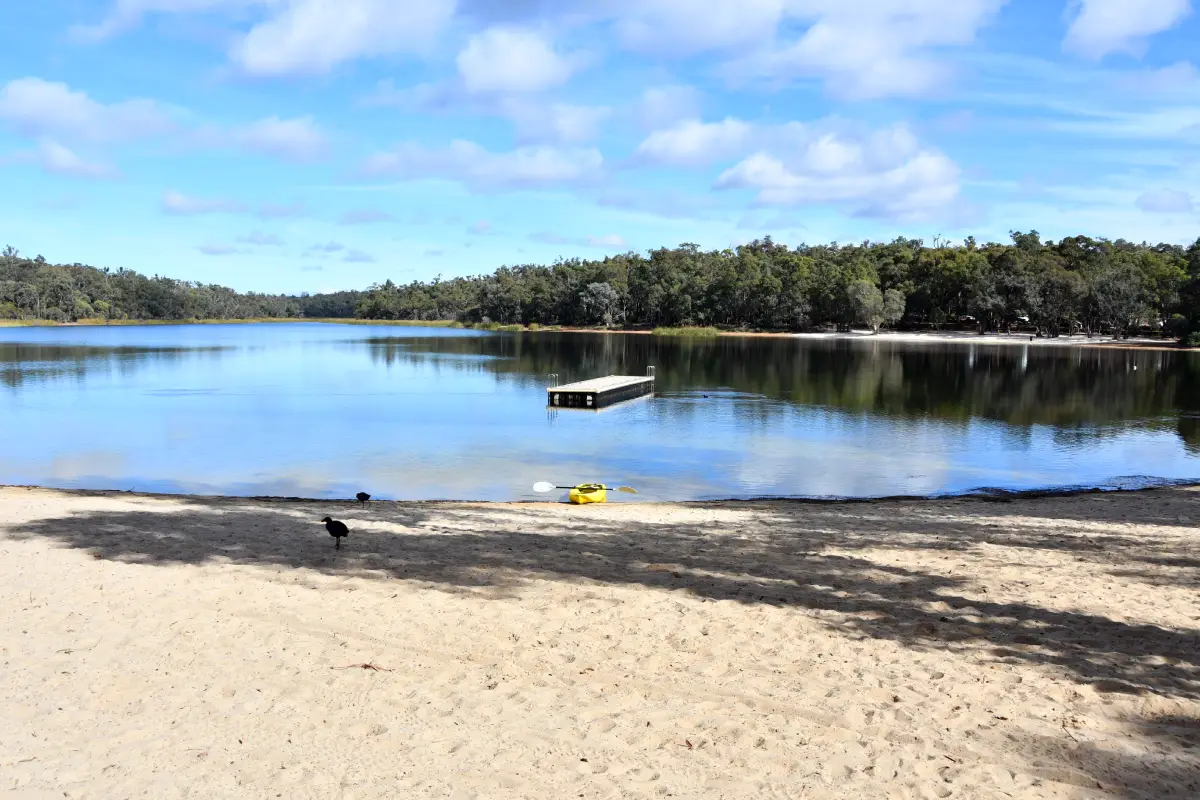 lake with swimming pontoon and canoes by sandy beach