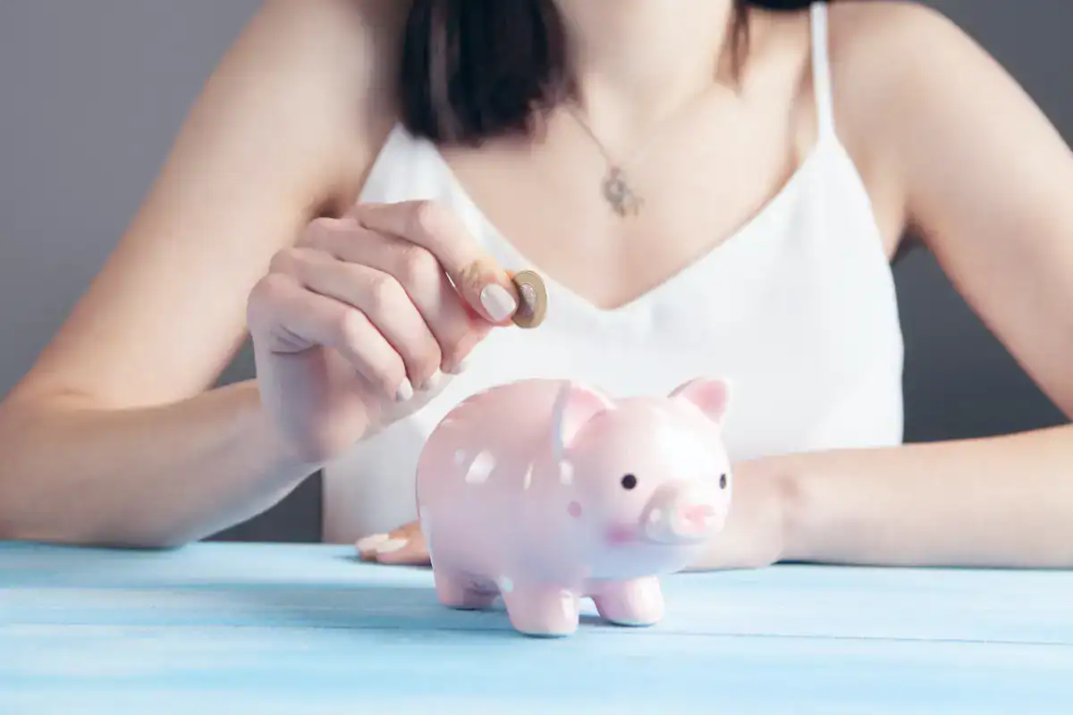 Ultimate Guide to Budgeting for Your Western Australia Adventure 1 woman in white putting coins into pink piggy bank