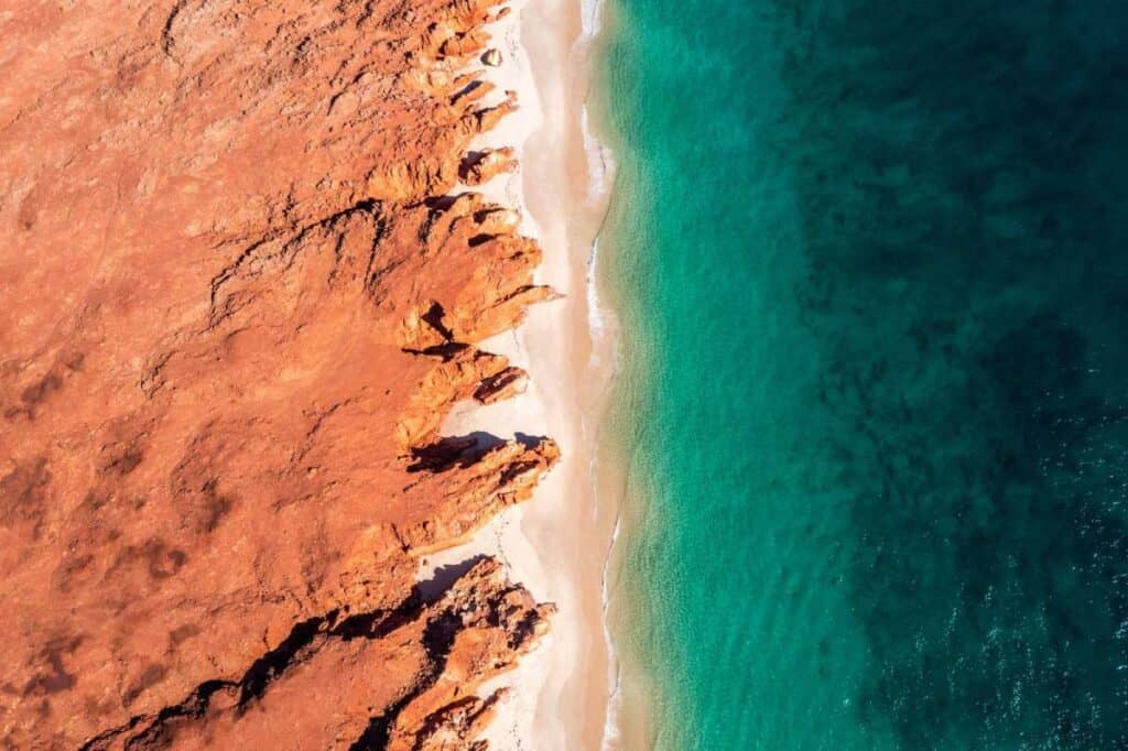 Can You Visit the Kimberley Without a 4WD? (Yes — Here’s How) 5 aerial view from air kimberley plane looking down onto red rocks white sand and turquoise ocean