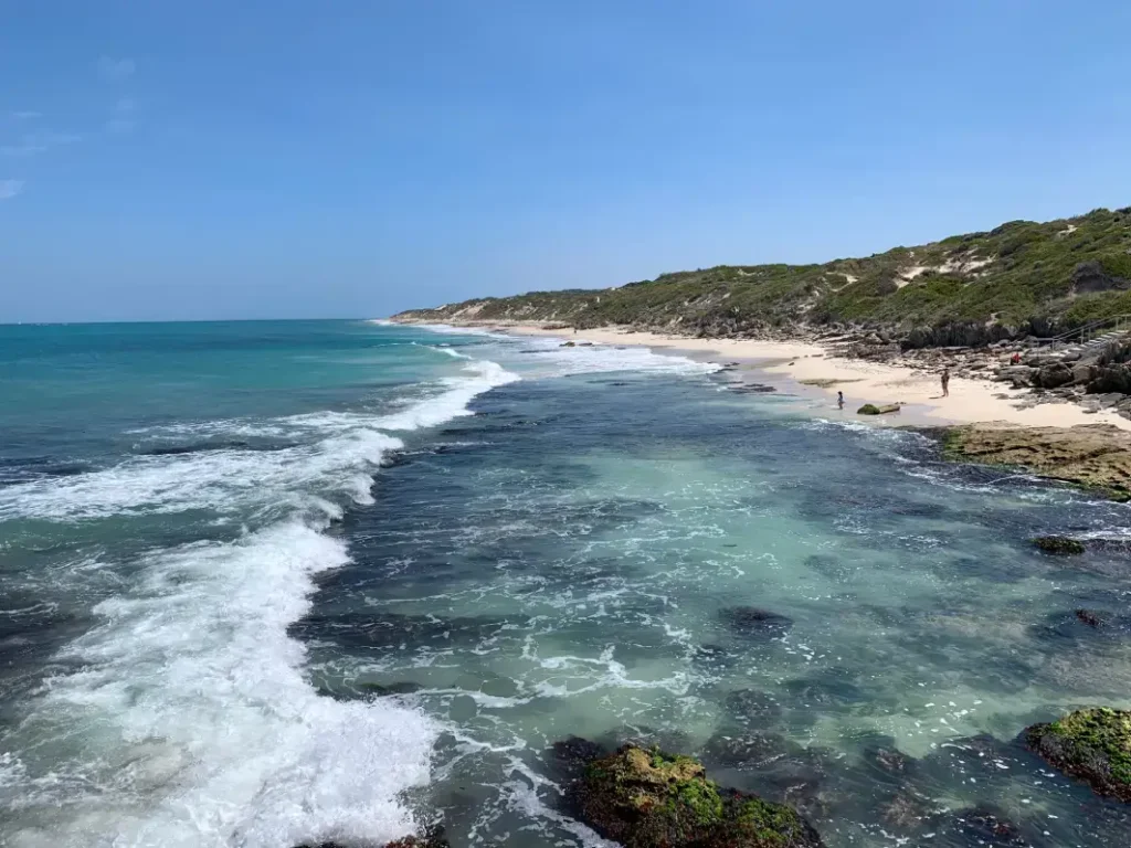 long stretch of beach with calm crystal clear water showing exposed reef at burns baech