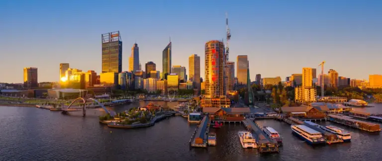 Perth Travel Guide: Is Perth Worth Visiting? (+ Things to Do, Where to Stay & Planning Tips) 1 aerial view of elizabeh quay in perth from south perth at sunset with tall buildings glowing in yellow light