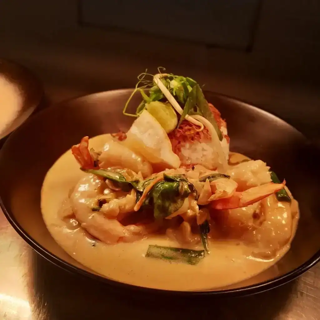 The Best Kalbarri Restaurants, Bars, and Cafes: My Guide for 2026 15 A bowl of seafood curry with large prawns and vegetables in a creamy yellow sauce, served with rice and garnished with fresh herbs