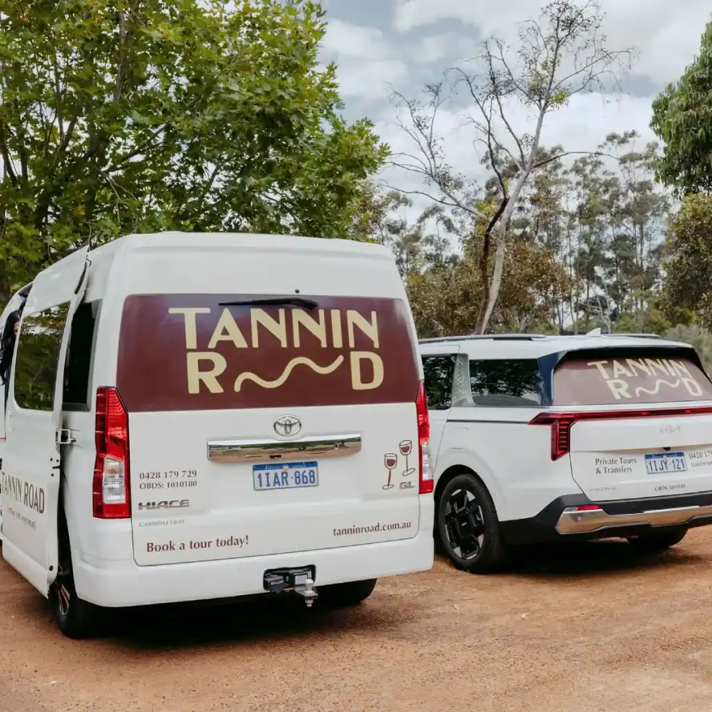 Best Wine Tours in Margaret River: Top Tours Compared (Plus Tips for Choosing the Right One) 6 a mini bus and car parked at a winery with the words tannin road written on them